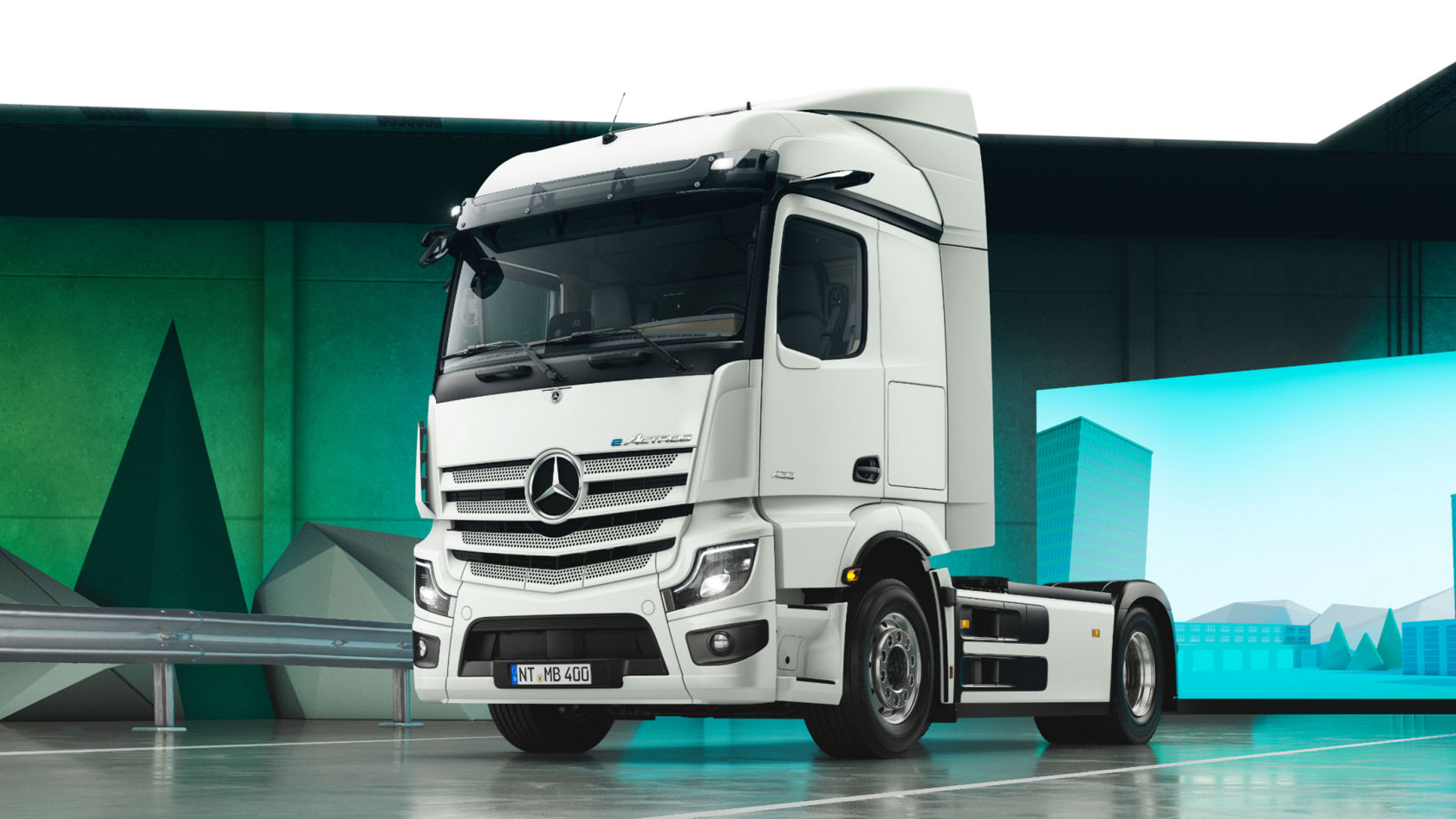 A white eActros from Mercedes-Benz Trucks stands on a shiny surface in a room with green and blue walls decorated with geometric shapes. The truck is shown from the front right, which makes its side view and the shiny rims easily visible.