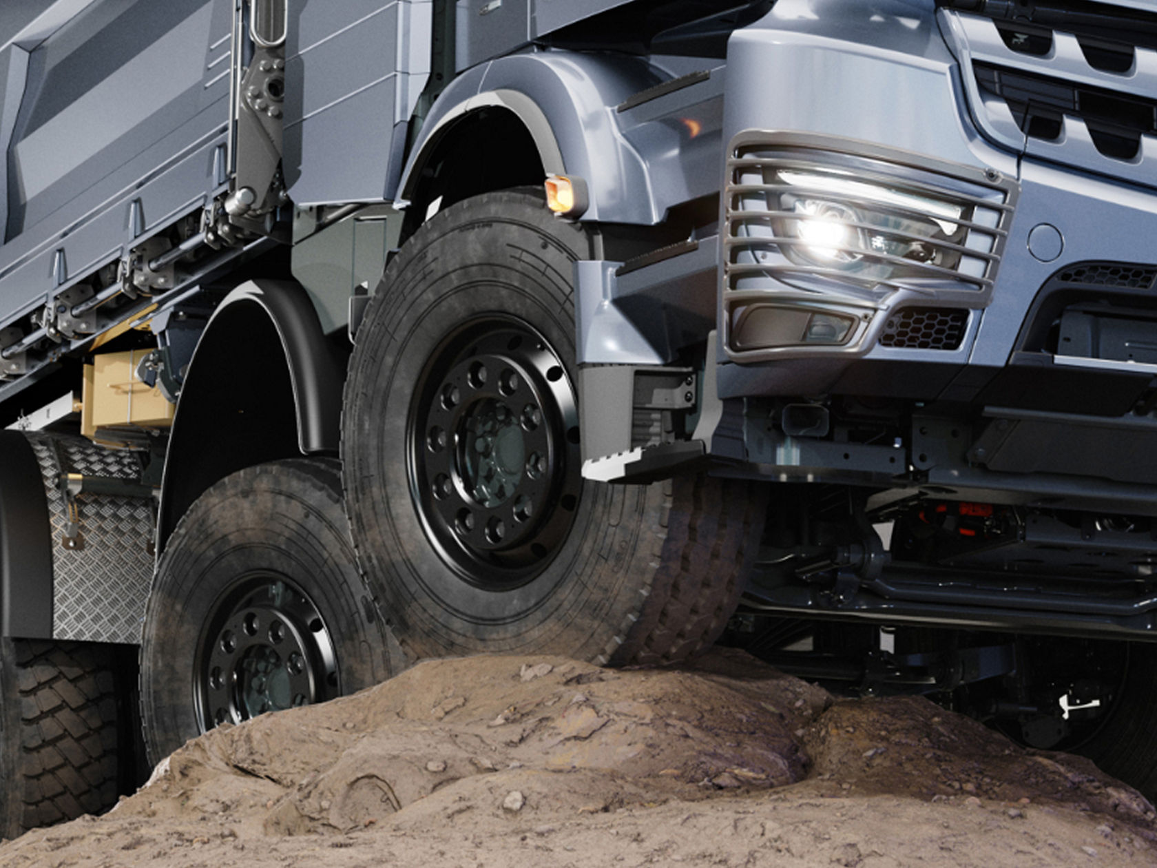 The image shows a section of an eArocs 400 driving over a dirt hill. The truck has large tyres and a robust suspension, which indicates that it is designed for use on the construction site.