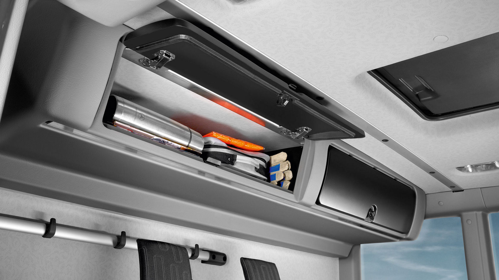 Close-up of a stowage compartment in an Econic. Various items are visible in the open compartment.