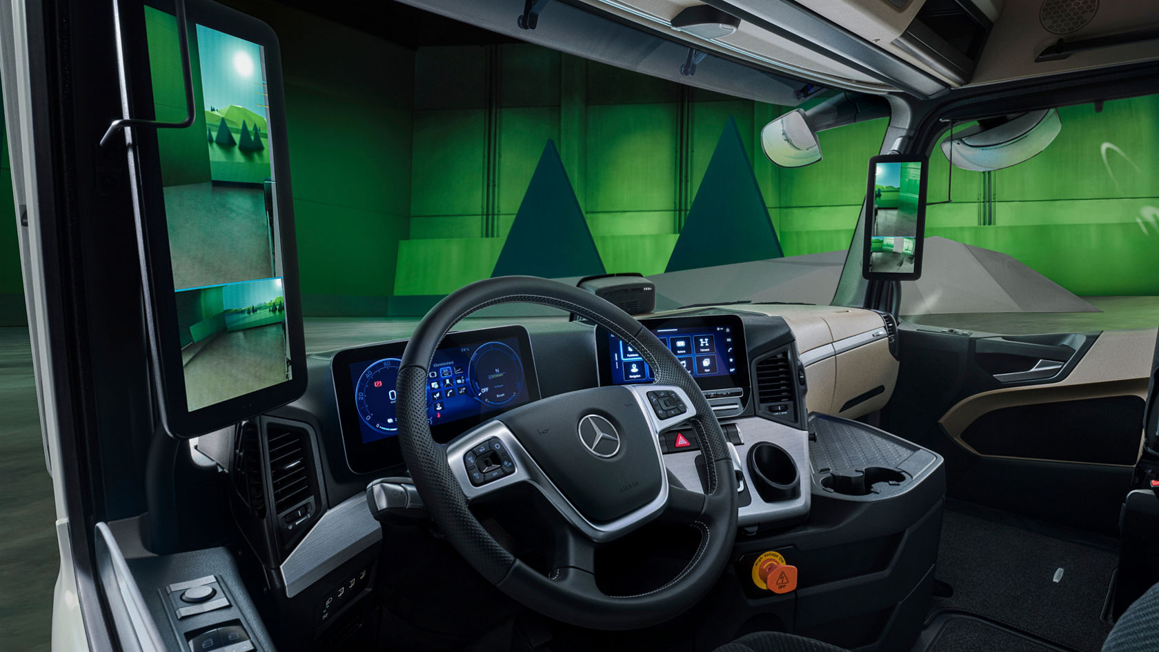 The image shows the modern interior of the eActros from Mercedes-Benz Trucks with a digital cockpit and two large screens that replace the exterior mirrors. In the background is a green wall with geometric shapes that represents a stylised landscape.