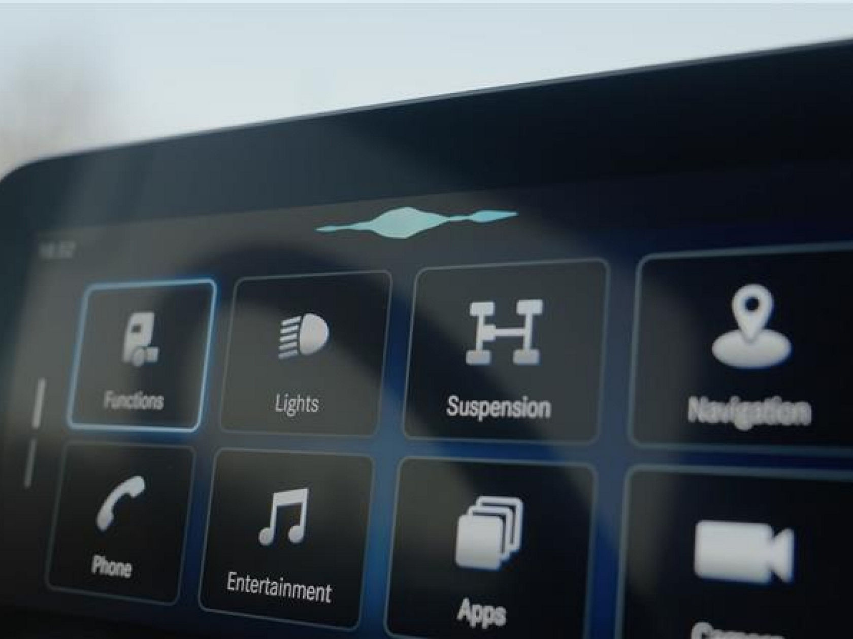 The image shows a section of the infotainment screen in the Mercedes-Benz Trucks eActros, on which various functions such as “Functions”, “Lights”, “Suspension”, “Navigation”, “Phone”, “Entertainment”, “Apps” and “Camera” are shown as symbols. A blue waveform at the top indicates active voice control.