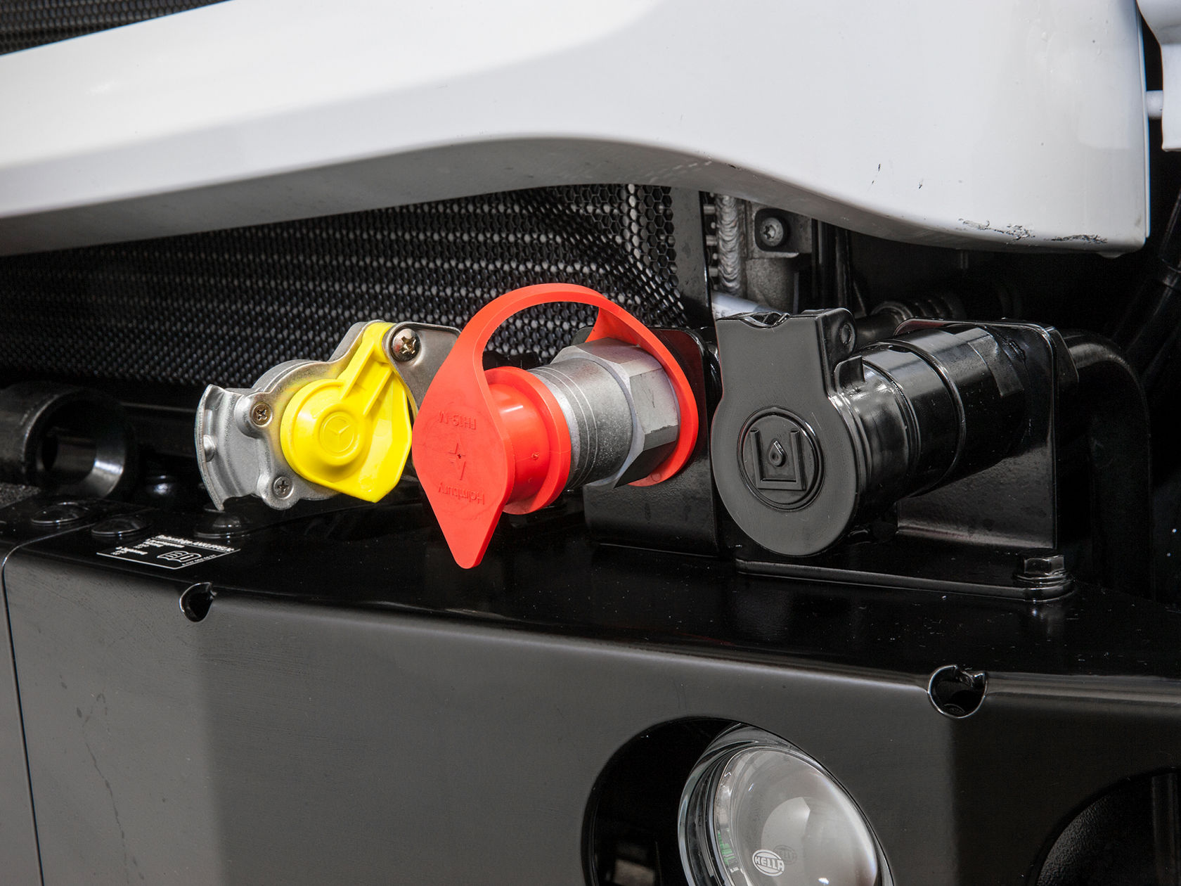 Close-up of the front of a white Unimog showing various connections.