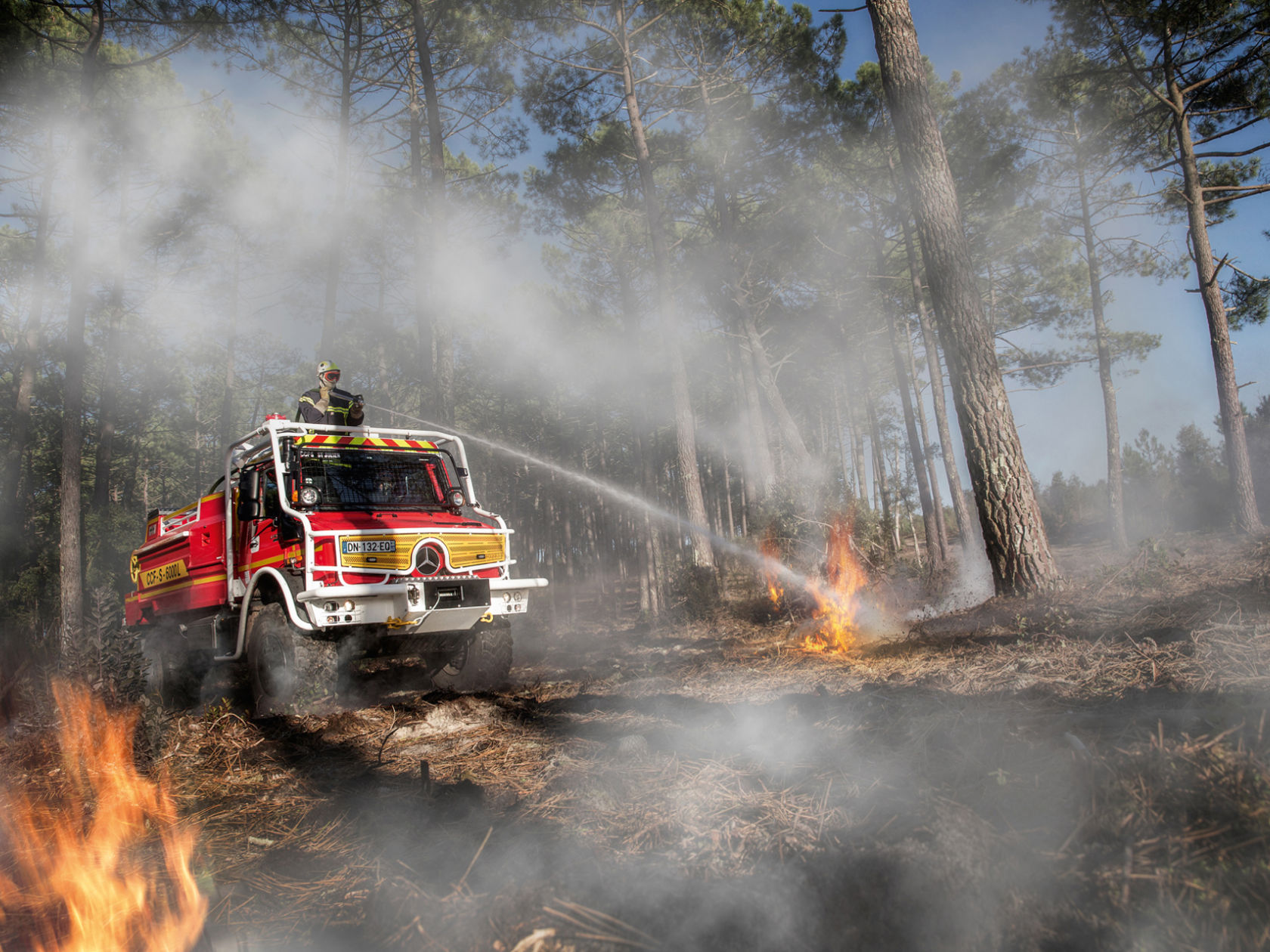 A red Unimog extinguishes a forest fire.