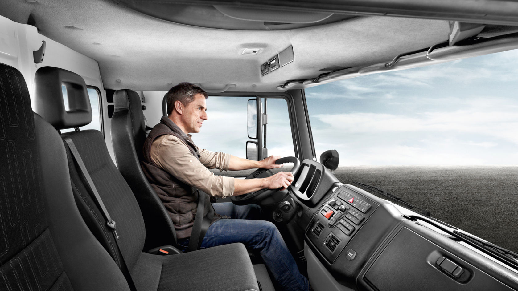 View into the cab of a Unimog. Man sitting at the wheel and operating the vehicle.