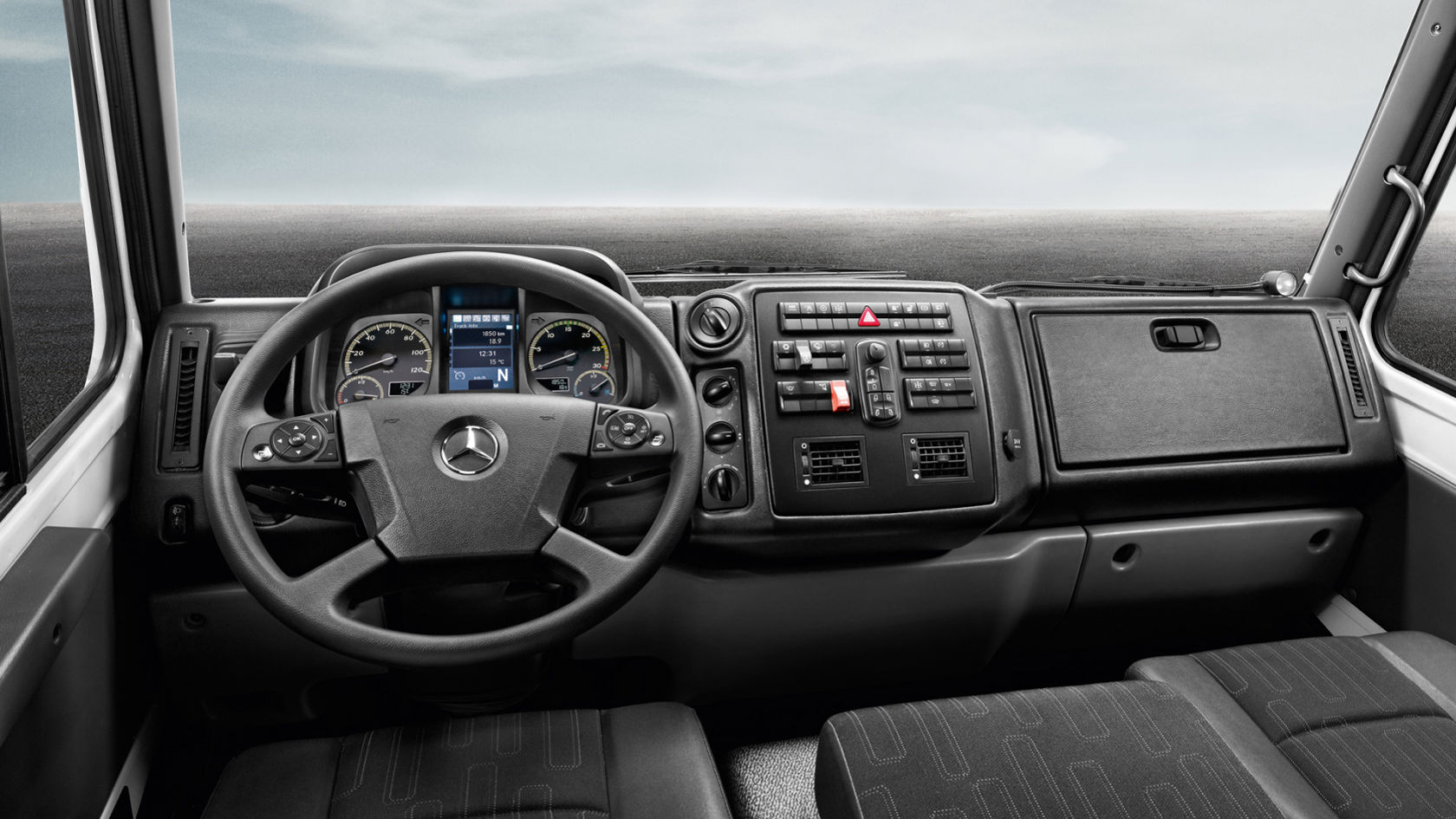 The dashboard of a Unimog with steering wheel, instrument display, and various control elements can be seen in the image.