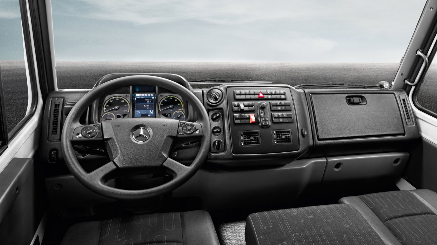 The dashboard of a Unimog with steering wheel, instrument display, and various control elements can be seen in the image.