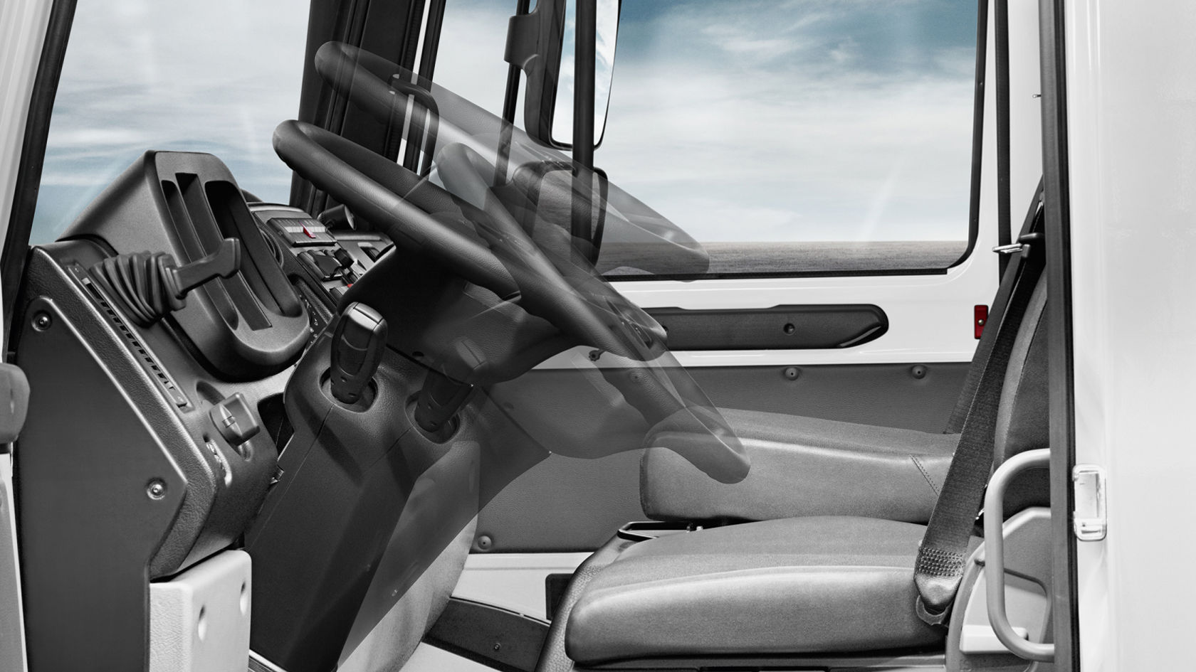 The cab of a Unimog with steering wheel, gearshift lever and front passenger seat.
