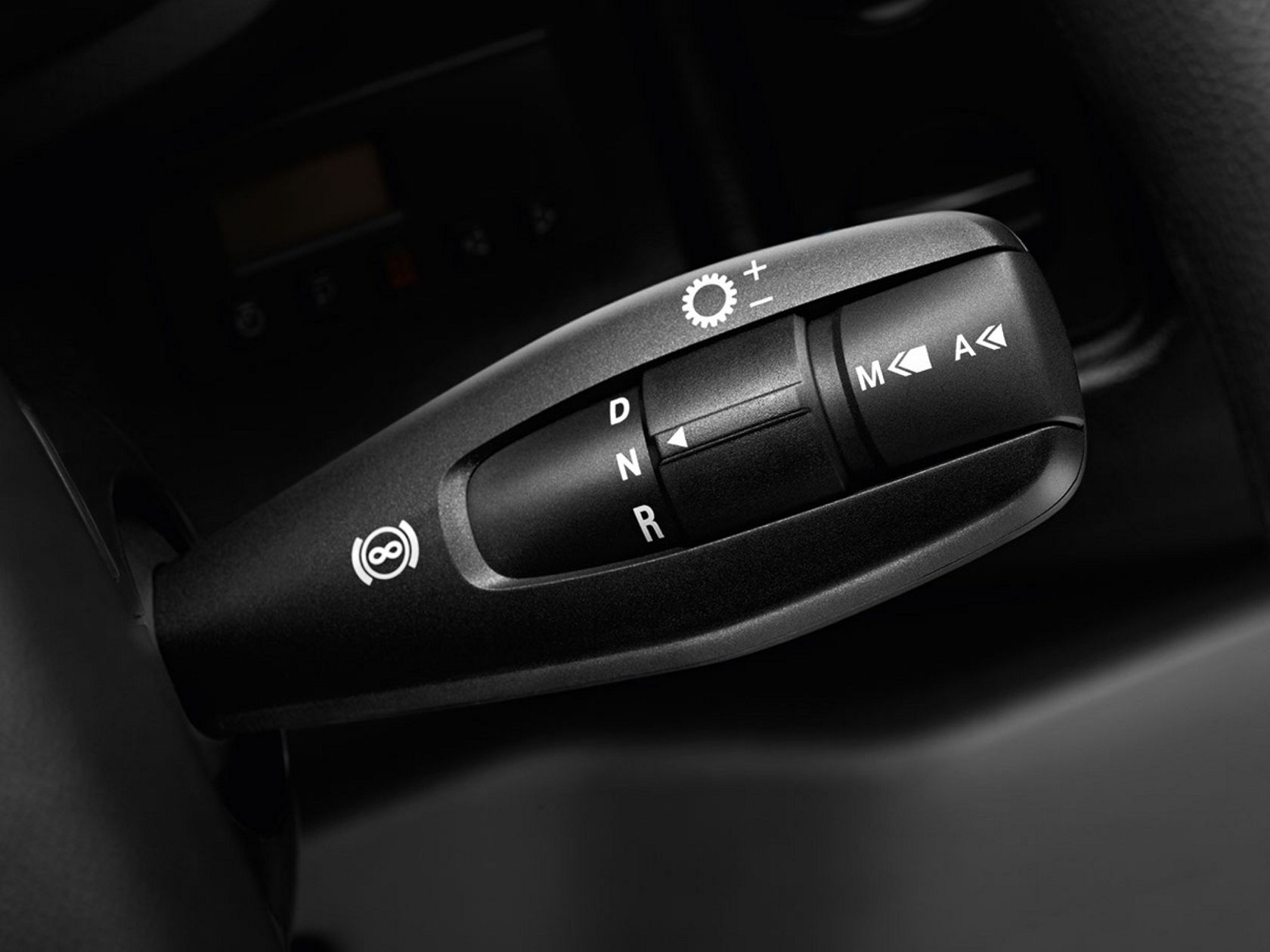 Close-up of a black gearshift lever with different markings for gear ranges. The lever shows the letters D, N and R as well as the plus, minus and parking brake symbols.