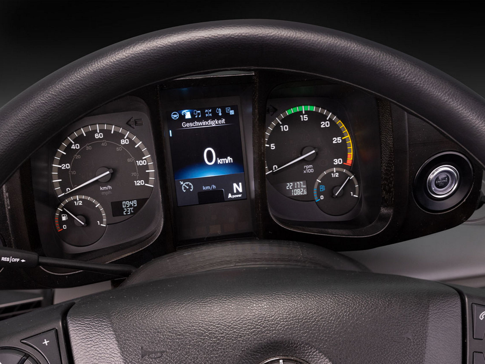 Close-up of a dashboard with speedometer, rev counter and a digital display showing the speed. The steering wheel is shown at the top of the picture.