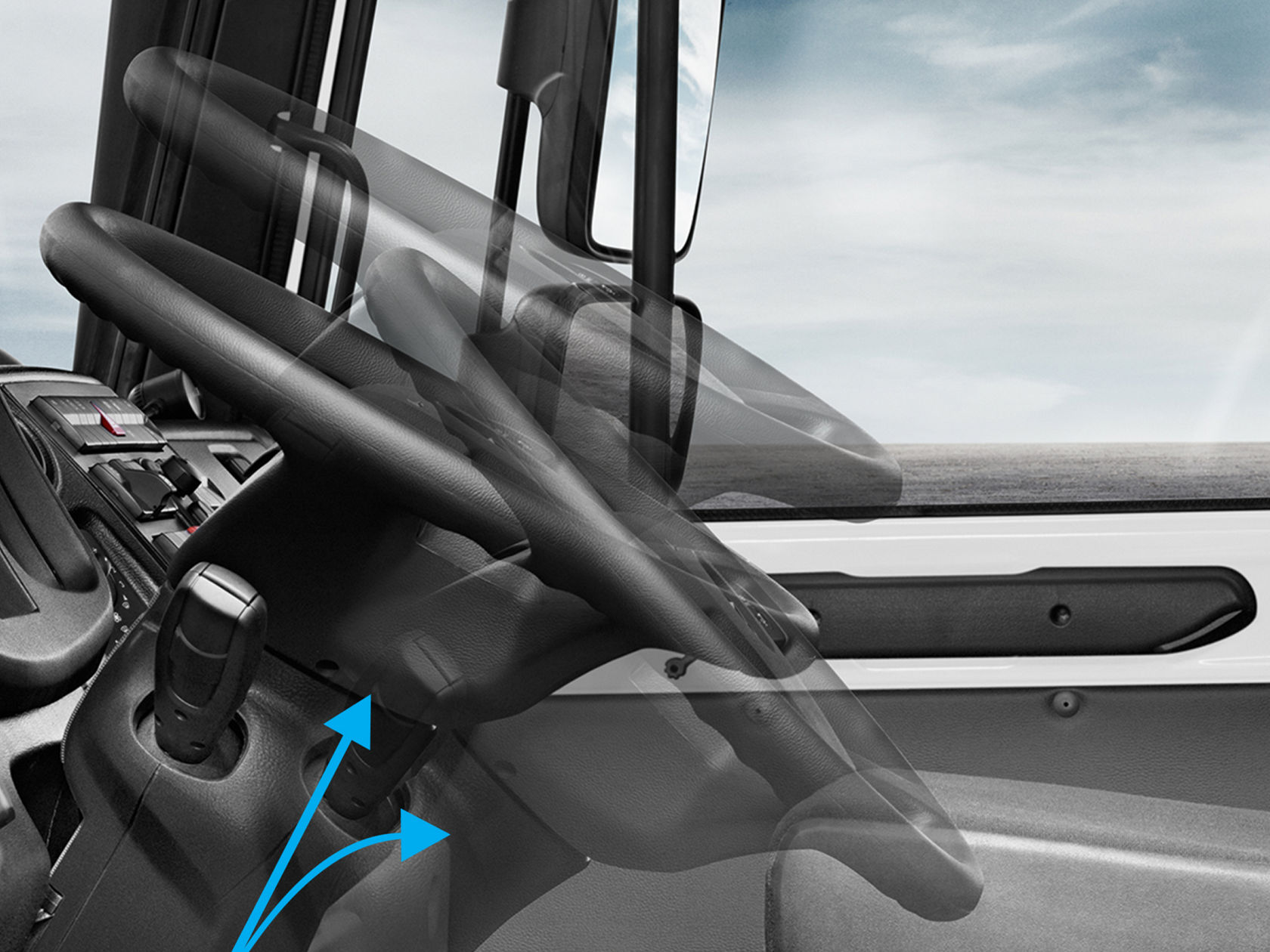 The interior of a vehicle cab with two steering wheels, a dashboard and a digital display in the middle. The seats are black and the dashboard is greenish-grey. The second steering wheel shows that the steering wheel position can be adjusted from the driver’s side to the front passenger side as required.