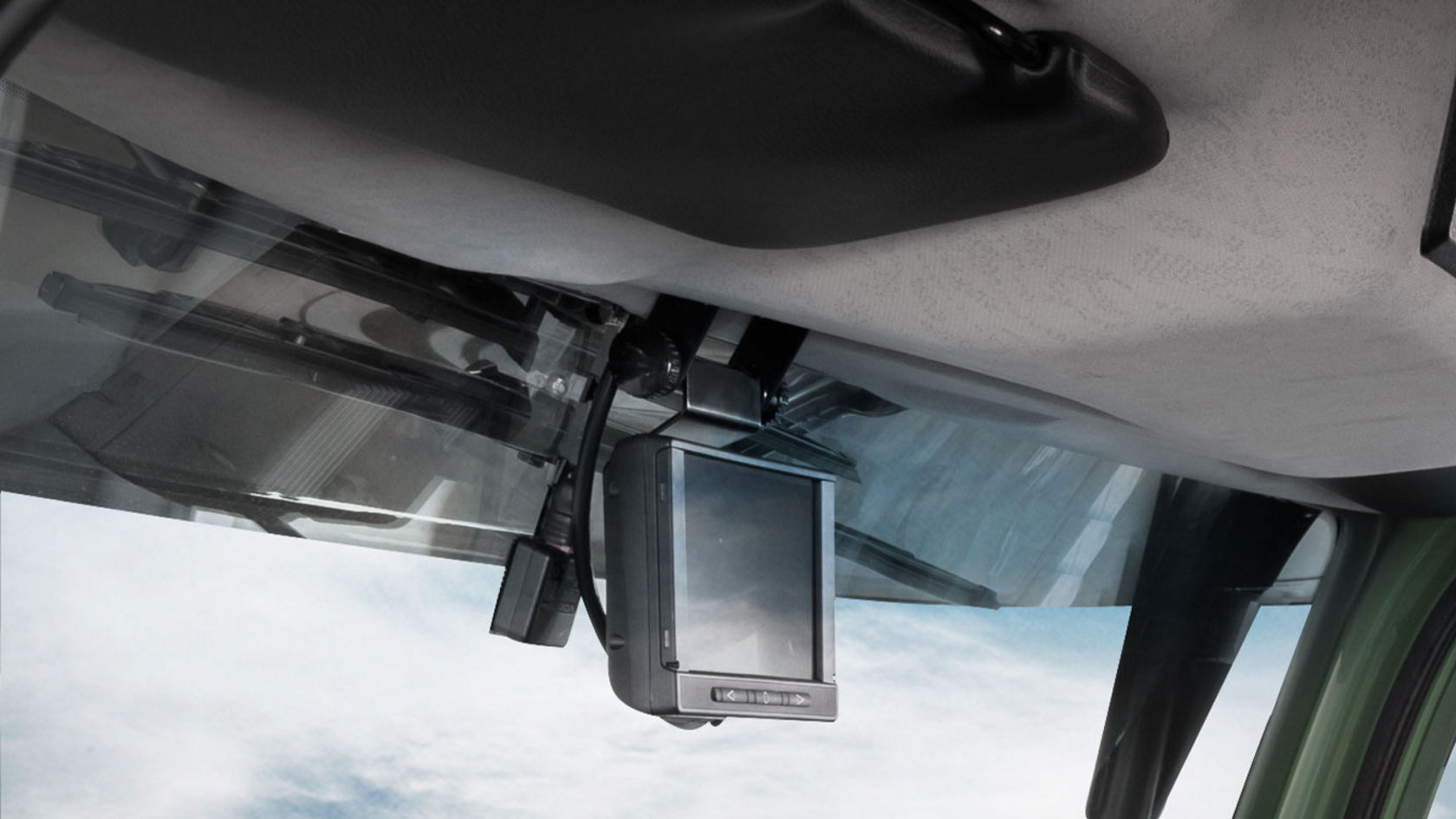 A small screen is mounted on the windscreen of a Unimog. The sky is visible through the windscreen.